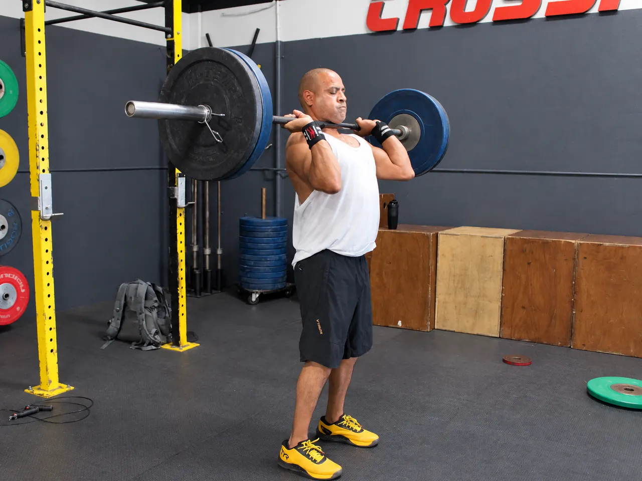 A member holding a barbell at his shoulders, practicing the clean